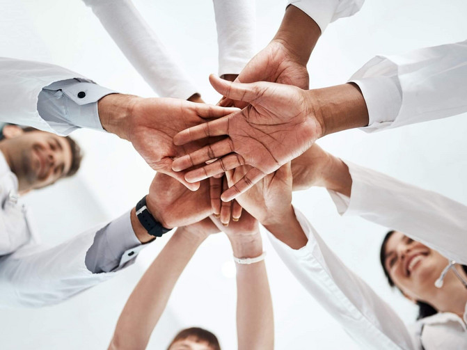 Menschen stehen im Kreis und legen ihre Hände übereinander