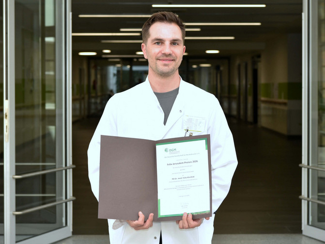 Auf dem Porträt ist Dr. Felix Kleefeld zu sehen, der seine Auszeichnung in den Händen hält.