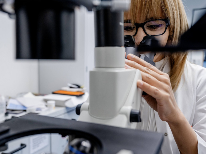 Eine Frau forscht an einem Mikroskop