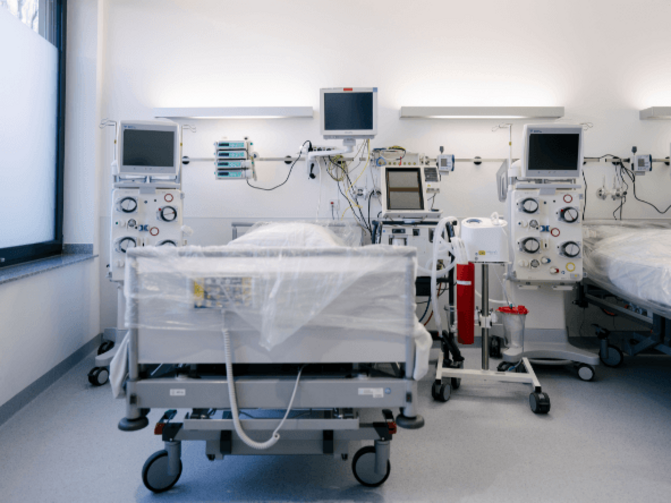 Auf dem Bild ist ein leeres Krankenbett in einem Krankenhauszimmer zu sehen.